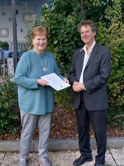 Pfarrer Geißlinger überreicht Delia Kappes eine Urkunde zum Dienstjubiläum